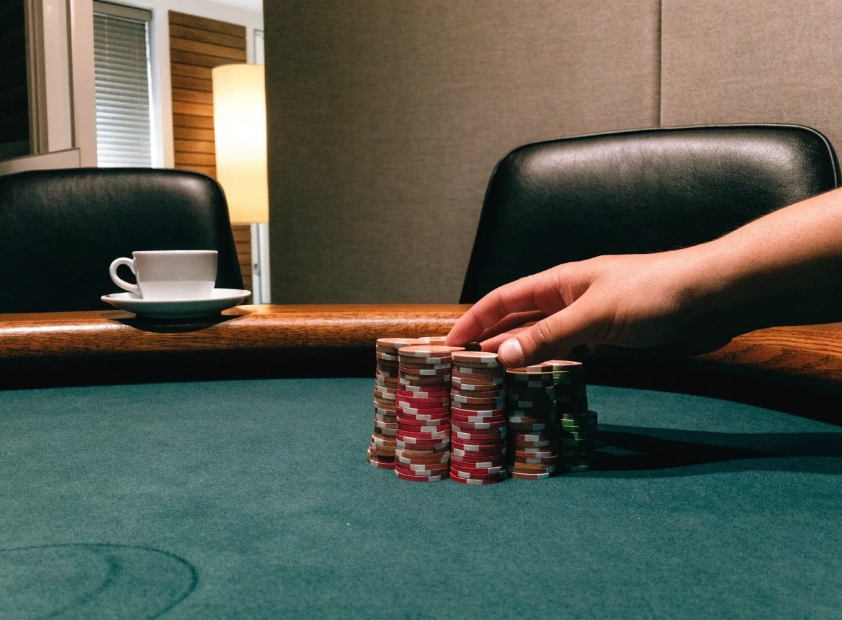 Zbliżenie na filc stołu pokerowego z żetonami i przyciskiem rozdającego