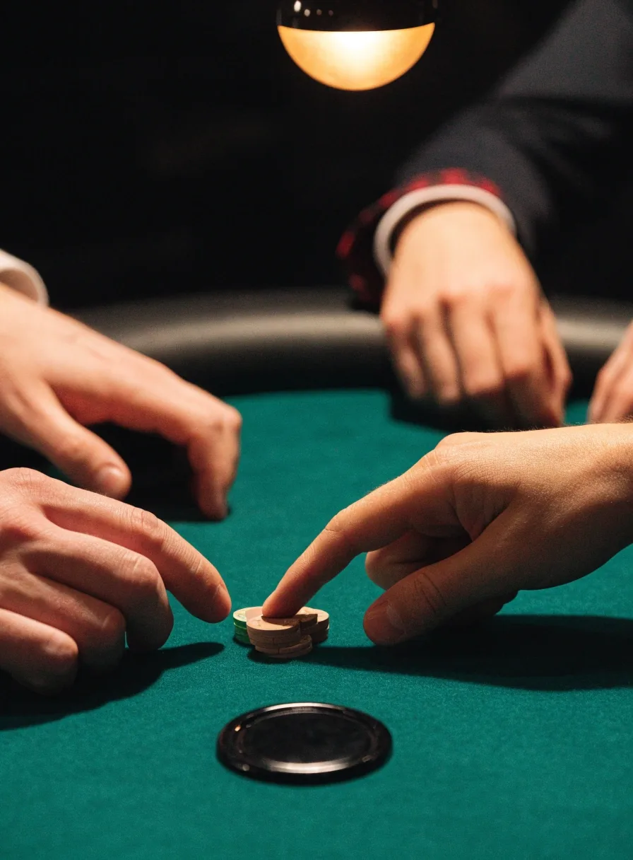 Detal sali pokerowej: żetony rozłożone na suknie obok przycisku rozdającego